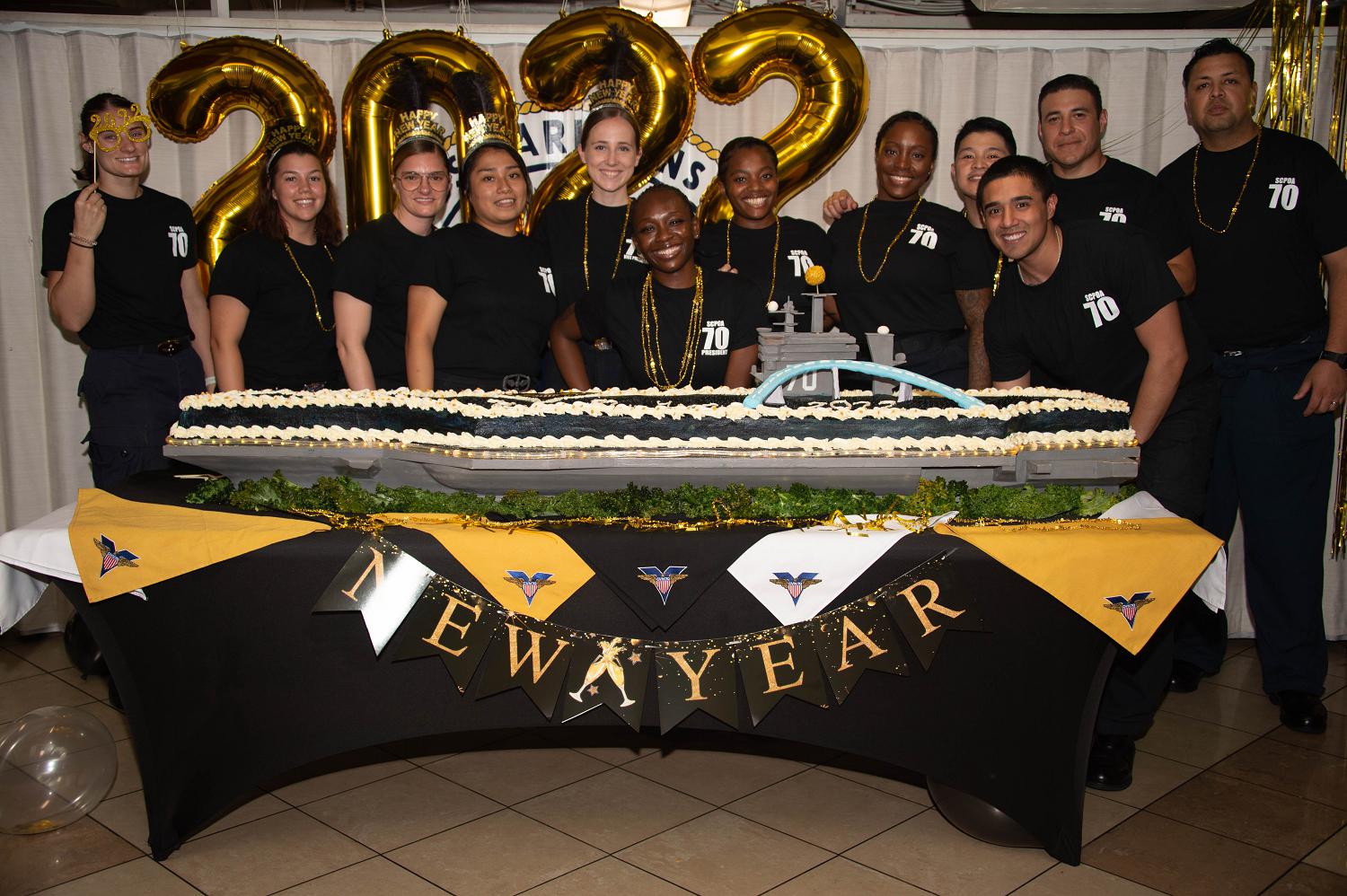 211231-N-EE352-1104 PHILIPPINE SEA (Dec. 31, 2021) Sailors assigned to Nimitz-class aircraft carrier USS Carl Vinson (CVN 70), pose next to a cake in the mess decks during New Year’s Eve event, Dec. 31, 2021. Carl Vinson Carrier Strike Group is on a scheduled deployment in the U.S. 7th Fleet area of operations to enhance interoperability through alliances and partnerships while serving as a ready-response force in support of a free and open Indo-Pacific region. (photo by Mass Communication Specialist Seaman Leon Vonguyen)